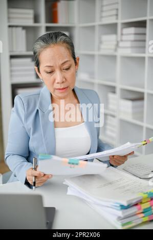 Stressige Geschäftsfrau, die sich wegen der Überlastung der Papierarbeit aufgeregt und müde fühlt. Stockfoto