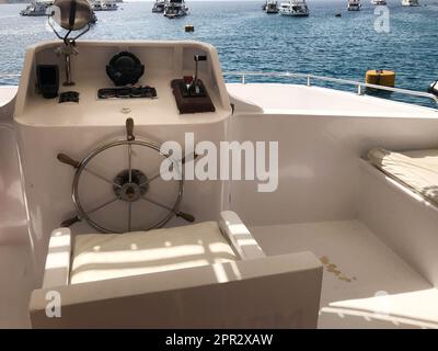 Die Kabine des Kapitäns auf einem Schiff, Boot, Kreuzfahrtschiff mit Lenkrad, Armaturenbrett mit Seekompass und Instrumenten zur Kontrolle gegen das blaue Meer und Stockfoto