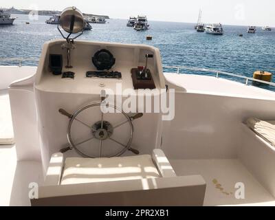 Die Kabine des Captains auf einem Schiff, Boot, Kreuzfahrtschiff mit Lenkrad, Armaturenbrett, Sessel, Marinekompass und Instrumenten zur Kontrolle gegen den Rücken Stockfoto