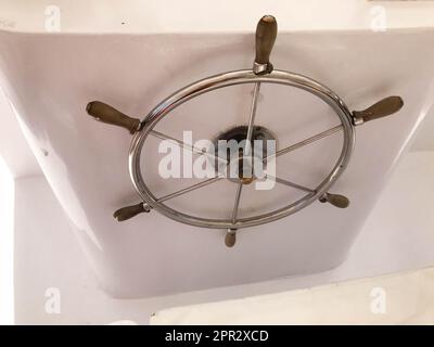 Verchromtes, rostfreies, glänzendes Lenkrad aus Metall mit Holzgriffen in der Kabine des Kapitäns zur Kontrolle auf dem Schiff, Boot, Kreuzfahrtschiff. Stockfoto