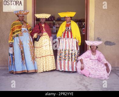 OTJIWARONGA, NAMIBIA - 30. MÄRZ 2023: Herero-Frauen tragen Ohorokova, ein viktorianisches Kleid mit bunten Mustern und einem Kuhhornmütze. Stockfoto