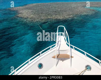Die Nase, die Vorderseite der weißen Yacht, das Boot, das Schiff, das auf dem Jig steht, Parken, Anker im Meer, das Meer mit blauem Wasser mit Korallen Stockfoto