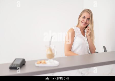 Rezeptionistin in einem Schönheitssalon, die mit einem Kunden telefoniert. Stockfoto