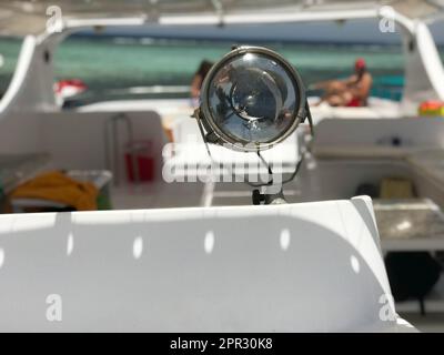 Eine große Lampe, ein Scheinwerfer, ein Suchscheinwerfer auf einem Boot, ein Schiff vor dem Hintergrund einer wunderschönen tropischen Landschaft eines blauen Salzmeers. Stockfoto