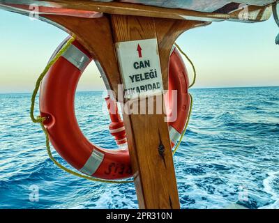 Ein orangefarbenes Rettungsboot, das am Deck des Schiffes befestigt ist. Gummischutzausrüstung bei Überschwemmungen von Menschen. Schwimmen unter Wasser im Meer. Stockfoto