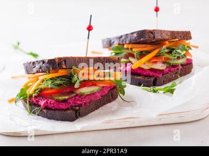 Glutenfreie vegane Sandwiches mit Rüben-Hummus, rohem Gemüse und Sprossen Stockfoto