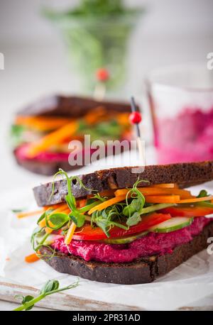 Glutenfreie vegane Sandwiches mit Rüben-Hummus, rohem Gemüse und Sprossen Stockfoto