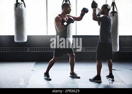 Stehen Sie für das, woran Sie glauben. Ein männlicher Boxer, der seine Bewegungen mit seinem Trainer übt. Stockfoto