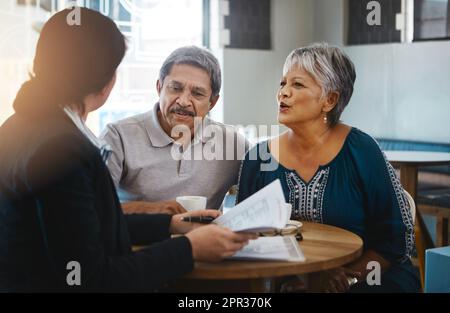 Wir schauen uns unsere finanziellen Möglichkeiten an. Ein Seniorenpaar trifft sich mit einem Finanzberater. Stockfoto