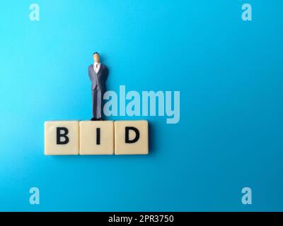 Miniatur-Menschen und Spielzeug-Wort mit dem Wort GEBOT auf blauem Hintergrund. Stockfoto