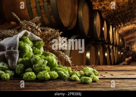 Frischer Hopfen und Weizenspikes auf einem Holztisch im Bierkeller Stockfoto