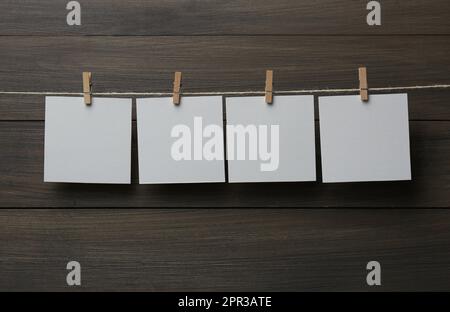 Kleiderschränke mit leeren Notizzetteln auf Garn vor Holzhintergrund. Platz für Text Stockfoto