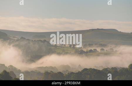 Ein nebeliger Morgen mit Nebel in den Tälern des English Peak District, Wolken um die Bäume, die durch eine Temperaturinvertierung an einem frühen Herbsttag verursacht werden Stockfoto