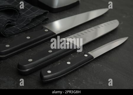 Satz scharfe Messer auf schwarzem Tisch, Nahaufnahme Stockfoto