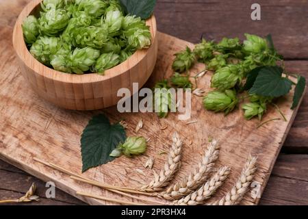 Frischer grüner Hopfen und Weizenohren auf einem Holztisch Stockfoto