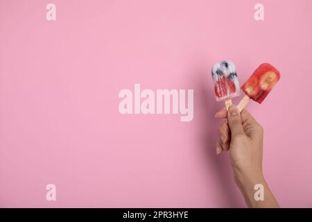 Eine Frau mit Beereneis auf rosa Hintergrund, Nahaufnahme. Platz für Text Stockfoto