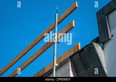 Fallschutzgerüst auf einer Baustelle. Dach mit Holzgeländern an der Dachkante, die an den Dachtrassen des Gebäudes eingehakt sind. Stockfoto