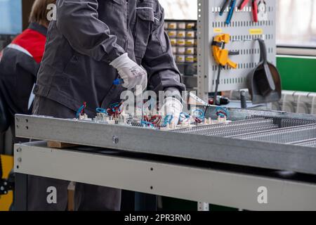 Perm, Russland - 25. April 2023: Arbeiter, der Ladestationen für Elektrofahrzeuge in der Werkstatt zusammenstellt Stockfoto