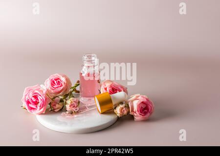 Kosmetikprodukt auf Rosenölbasis in einer offenen Glasflasche und einer gefüllten Pipette. Pastellfarbener Hintergrund mit einem Kopierbereich. Natürliche Kosmetik Stockfoto