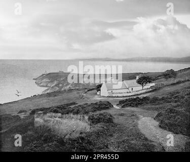 Ein Blick aus dem späten 19. Jahrhundert auf Dublin Bay von Howth Head mit Cottages und einem fernen Baily Lighthouse Ein neuer Turm, 41 Meter (134 Fuß) über dem Meer, entworfen von George Halpin Senior, dem Inspektor of Works des Unternehmens, wurde am 17. März 1814 fertiggestellt. Stockfoto