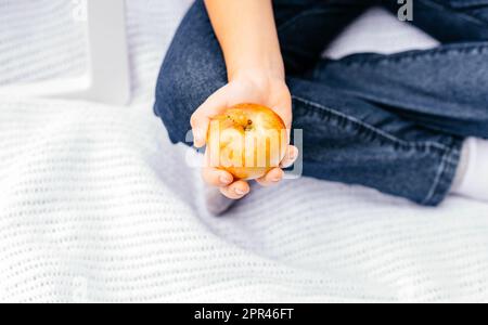 Ein Kind auf einem Picknick hält einen reifen, saftigen Apfel in der Hand. Gesundes Essen, Vegetarismus, Diätkonzept. Stockfoto