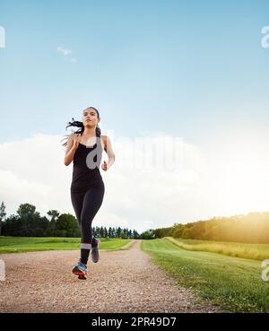 Verpflichten Sie sich, fit zu sein. Eine fitte junge Frau, die an einem wunderschönen Tag einen Lauf macht. Stockfoto