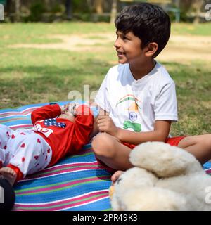 Zwei glückliche Jungs im Gesellschaftspark, glückliche asiatische Brüder, die glücklich zusammen lächeln. Brüder spielen im Sommer draußen, beste Freunde. Kleinkind Baby bo Stockfoto