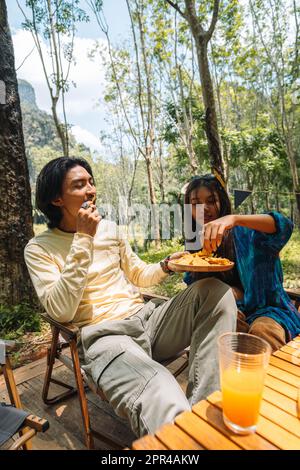 Vier internationale Freunde feiern im Sommer eine Party in der Natur, trinken Saft und essen Melonen Stockfoto