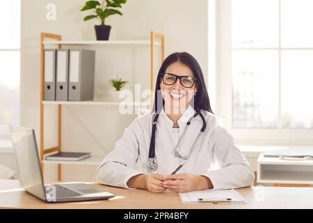 Porträt einer fröhlichen jungen, freundlichen Ärztin in weißer medizinischer Uniform, die in die Kamera schaut. Stockfoto