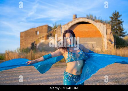 Orientalische Tänzerin in Blau mit Isis-Flügeln der gleichen Farbe, die draußen tanzt Stockfoto