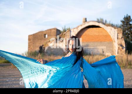 Orientalische Tänzerin in Blau mit Isis-Flügeln der gleichen Farbe, die draußen tanzt Stockfoto