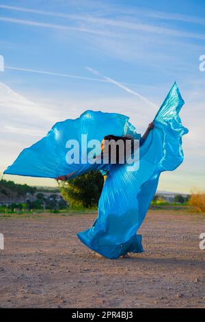 Orientalische Tänzerin in Blau mit Isis-Flügeln der gleichen Farbe, die draußen tanzt Stockfoto