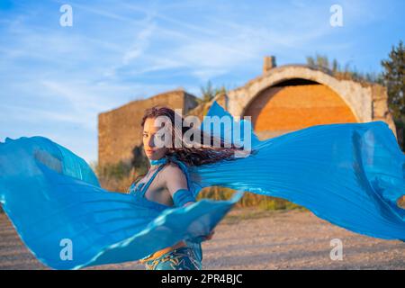 Orientalische Tänzerin in Blau mit Isis-Flügeln der gleichen Farbe, die draußen tanzt Stockfoto