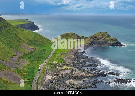 Aus der Vogelperspektive: Bus und Fußgängerweg zum Giant's Causeway mit Blick auf das Meer und blauem Himmel in Nordirland, Großbritannien. Stockfoto