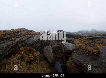 Gritstone Felsformationen in der Nähe von Sandy Heys, am Rand von Kinder Scout in Heyfield im Derbyshire Peak District, an einem regnerischen, nebligen und stürmischen Tag Stockfoto