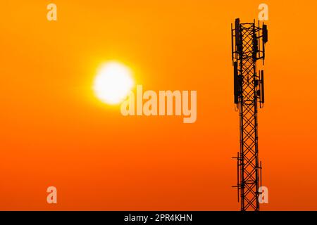 5G-Mobilfunkantenne für digitale Mobilfunkmasten auf klarem Hintergrund mit orangefarbenem Himmel bei Sonnenuntergang. Stockfoto