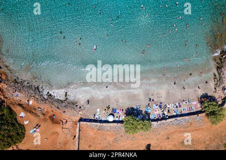 Blick von oben auf Touristen an einem kleinen Strand mit kristallklarem, blauem Ozean auf der Insel Kreta, Griechenland Stockfoto