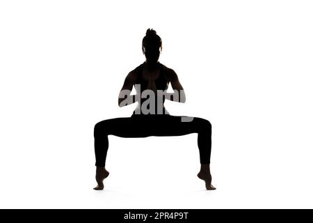 Eine Frau macht Yoga vor einem weißen Hintergrund. Stockfoto