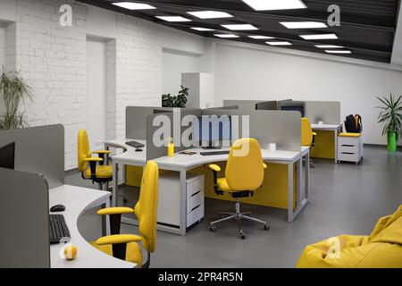 IT-Büro mit Arbeitsplätzen für Mitarbeiter Entwickler mit gelben Stühlen und Computern. Stockfoto