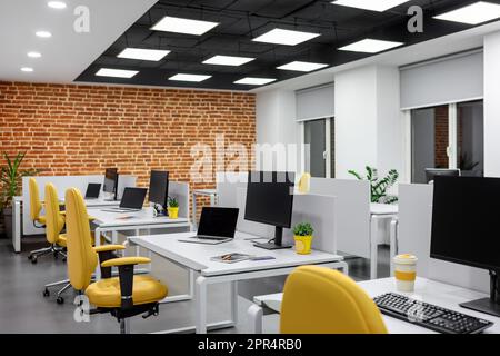 IT-Büro mit Arbeitsplätzen für Mitarbeiter Entwickler mit gelben Stühlen und Computern. Stockfoto