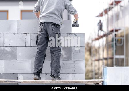 Ein Mauerwerk baut die Wand eines Gebäudes aus Betonziegeln und -Blöcken Stockfoto