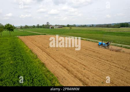 Castell'Arquato, Italien - April 2023 Landwirt, der auf gepflügtem, trockenem Feld einen Raupentraktor fährt, bevor er aus der Vogelperspektive sät Stockfoto