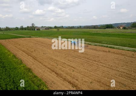 Castell'Arquato, Italien - April 2023 Landwirt, der auf gepflügtem, trockenem Feld einen Raupentraktor fährt, bevor er aus der Vogelperspektive sät Stockfoto