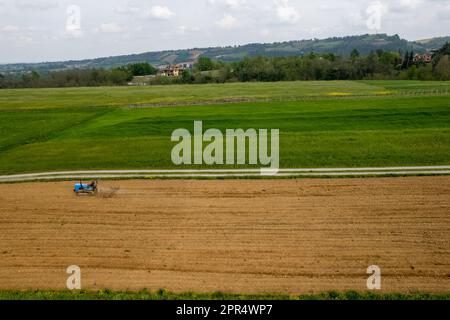 Castell'Arquato, Italien - April 2023 Landwirt, der auf gepflügtem, trockenem Feld einen Raupentraktor fährt, bevor er aus der Vogelperspektive sät Stockfoto