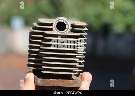 Zylinderkopf für kleinen Benzinmotor mit Kühlrippen und einem Schlitz zum Hinzufügen einer Zündkerze in der Hand Stockfoto