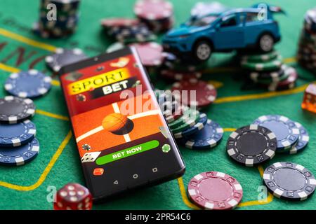 Kasino-Chips und Spielzeugauto, Smartphone mit Sportwetten Stockfoto