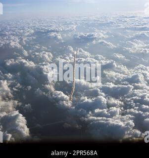 Luftaufnahme der Einführung des STS 51-A Shuttle Discovery. Das Startfeld kann als Lichtpunkt in der Mitte einer Wolkenmasse gesehen werden. Der Shuttle Discovery wird als Lichtpunkt an der Spitze einer Rauchsäule gesehen, die zwischen der dichten Wolkendecke umrandet ist. Stockfoto