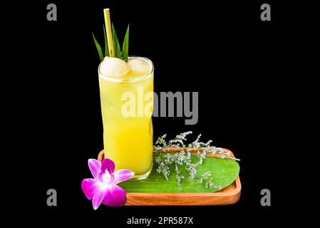 Lychee-Saft mit einer Scheibe Lychee-Frucht, mit Blüten auf schwarzem Hintergrund isoliert Stockfoto