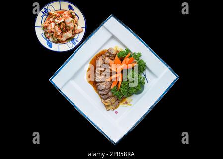 Gebratenes Schweinefleisch in Sojasoße serviert mit Knoblauch und Kimchi Stockfoto