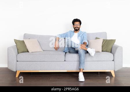 Entspannter, fröhlicher Ost-Typ, der zu Hause auf der Couch chillt Stockfoto